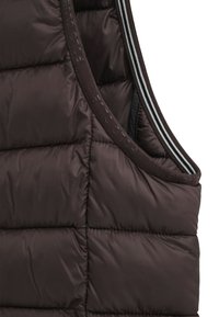 Brązowa kamizelka puchowa z poziomymi przeszyciami, gładką teksturą i kontrastowym ciemnoszarym wykończeniem z dwoma cienkimi białymi paskami.