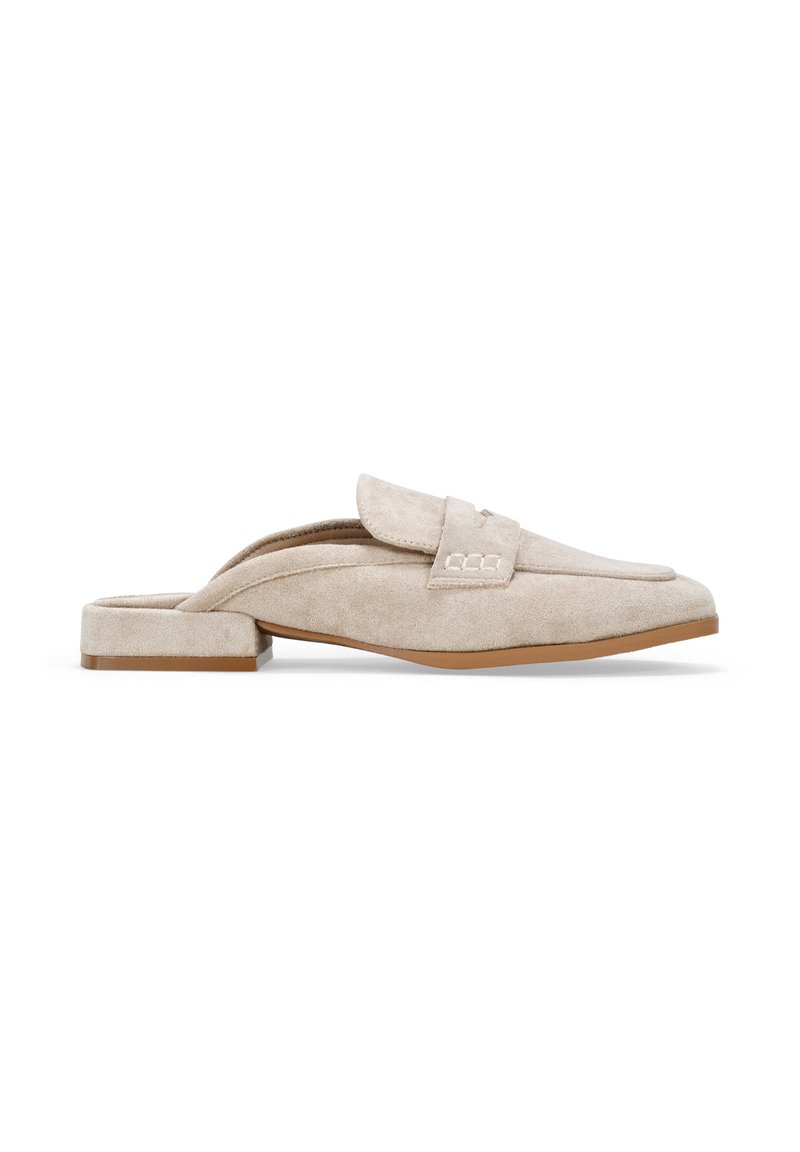 Mocasines de ante beige sin cordones con un tacón bajo, que presentan una parte superior ancha y detalles de costura en la parte delantera.
