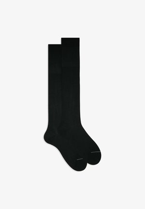 Schwarze knielange Socken aus glattem Material. Mit verstärkter Spitze und minimalen Nähten. Klassisches Design mit nahtlosem Abschluss.