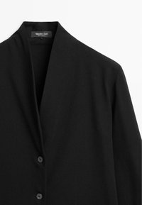 Zwarte jas met een sjawlboord, gemaakt van gladde stof, met een voorste knoopsluiting en een minimalistisch ontwerp. Geen zichtbare patronen of accenten.