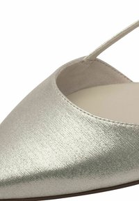 Metallisk silverfärgad spetsig tå platt sko med öppen häl och smal rem. Texturerad yta med subtil glans och slät innersula.