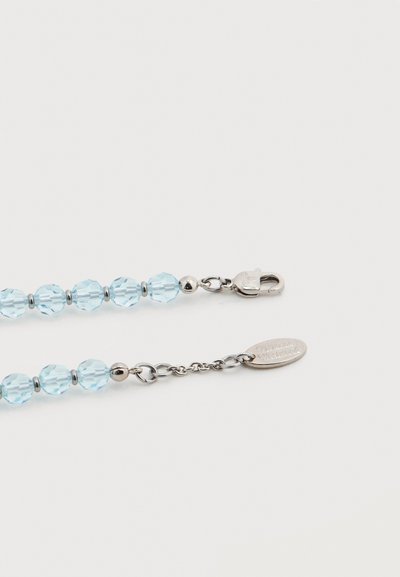 Φωτεινές γαλάζιες χάντρες με όψη διαμαντιού περασμένες σε ασημένια αλυσίδα με μεταλλικό κούμπωμα και μικρή οβάλ ετικέτα, με χαραγμένο κείμενο.