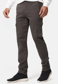 Cargo pants in dark gray, made of soft fabric, feature side pockets, slim fit, and are paired with black textured sneakers.