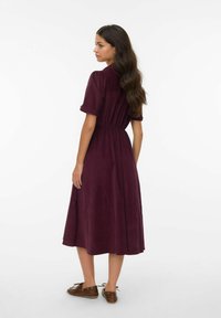 Bordeaux midi-jurk met korte opgerolde mouwen, een elastische taille en een vloeiende rok. Glad textuur en minimale details.