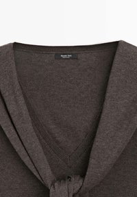 Dunkelbrauner Pullover mit V-Ausschnitt und Details in Form einer Schleife am Kragen, mit glatter Textur und geripptem Strickfinish. Markenlabel sichtbar.