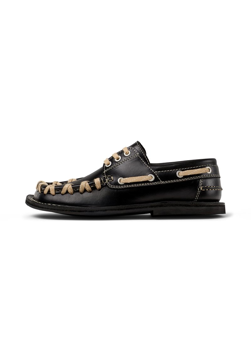 Scarpa nautica in pelle nera con lacci beige a contrasto, dettagli cuciti, suola in gomma e rinforzi in metallo per un supporto aggiuntivo.