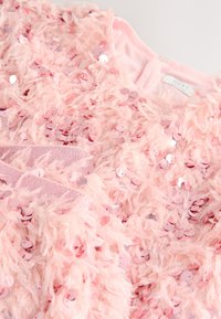 Pink feathery top adorned with sequins. Features a soft texture, round neckline, and a shiny, shimmering appearance.