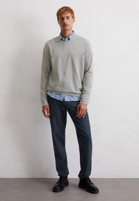 Grijze trui, lichtblauw overhemd met kraag, marineblauwe broek en zwarte schoenen. Casual kleding met een ontspannen pasvorm en een eenvoudig ontwerp.
