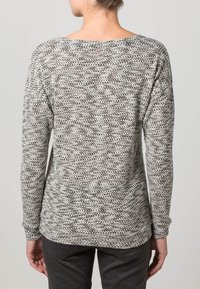 Grå och vit texturerad tröja med lång ärm och avslappnad baktill. Har en vid halsringning och ribbade ärmslut.