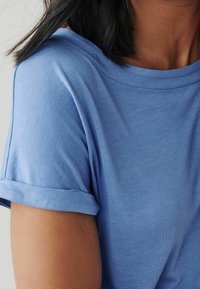 T-shirt azzurro chiaro a maniche corte con orlo arrotolato, texture morbida, scollo a girocollo e tessuto liscio con cuciture minime.