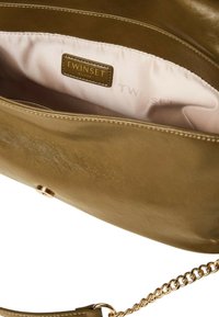 Olivgrüne Lederhandtasche mit glatter Textur, goldfarbenem Metall-Logo und beigem Innenfutter. Verfügt über einen Kettenriemen und einen Verschluss mit Schnapphaken.