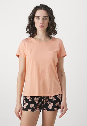 Peach cotton t-shirt with short sleeves and a chest pocket, paired with black floral-patterned shorts featuring pink flowers.