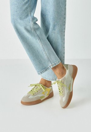 Baskets à lacets en mesh beige avec des accents vert citron et une semelle en caoutchouc. Dotées d'une languette rembourrée et d'un design texturé sur la tige.