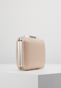 Blushfärgad handväska av slät material, med rektangulär form, silver detaljer och en minimalistisk design.