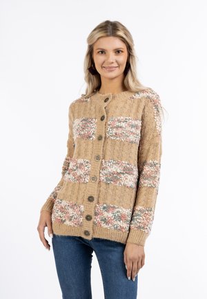 Strikket cardigan i beige med teksturerede blomsterlapper i pink og grøn. Har syv brune knapper og ribbede manchetter, som giver en behagelig pasform.