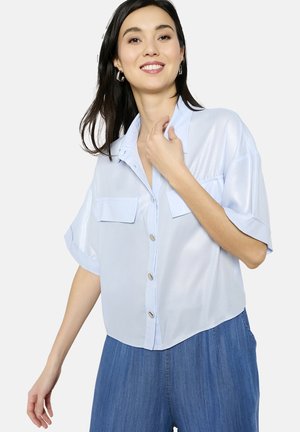 Light blue short-sleeve shirt made of shiny fabric, featuring a button-down front, two chest pockets, and a curved hem.