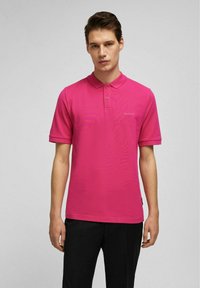 Korte mouw polo shirt in felroze, gemaakt van ademend materiaal. Beschikt over een klassieke kraag en een twee-knopenplacket, met logo-opdruk op de borst.