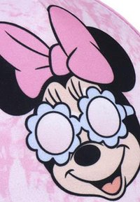 Minnie-Maus Charakterdesign mit einer pinken Schleife, großen runden Brillen mit floralen Akzenten, vor einem hellpinken strukturierten Hintergrund.