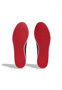 Zapatillas deportivas negras con una suela de goma roja texturizada que presenta un patrón hexagonal. Detalles en blanco a lo largo de los laterales y el talón.