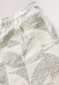 Szorty z fakturowanej tkaniny z beżowo-szarym wzorem kwiatowym. Elastyczny pas w talii z subtelnym detalem kieszeni po boku.