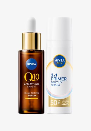 Braune Glas-Tropfflasche mit goldenem Deckel, beschriftet mit "Q10 Anti-Aging-Experte." Daneben eine weiße Flasche mit blauen Akzenten, beschriftet mit "2-in-1 Primer Daily UV Serum."