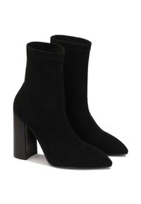 Bottines en daim noir avec bouts pointus et talon haut carré. Texture lisse, design ajusté, sans éléments métalliques ou ornements visibles.