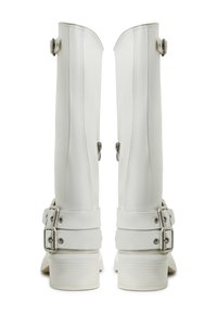 Białe wysokie buty o eleganckim designie, wykonane z gładkiego materiału. Wyposażone w srebrne klamry i zamki, z teksturowaną podeszwą dla lepszej przyczepności.