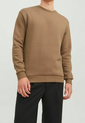 Brązowa bluza crewneck wykonana z miękkiego materiału, z prążkowanymi mankietami i dołem, w połączeniu z czarnymi spodniami. Minimalistyczny design, bez wzorów.