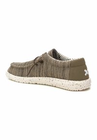 Zapatos de punto marrones con cordones elásticos, suela de goma blanca moteada y acento en el talón de color verde oliva. El interior presenta rayas en blanco y negro.