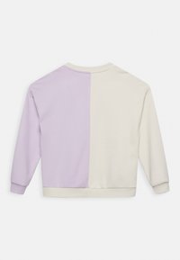 Sweatshirt com gola redonda, com o lado esquerdo em lilás e o lado direito em creme. Feito de algodão suave, apresenta mangas longas e um corte relaxado.