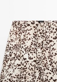 Pohodlné krátké pyžamo s leopardím vzorem v krémových a hnědých tónech, s elastickým pasem na šňůrku a lehkým, textured materiálem.