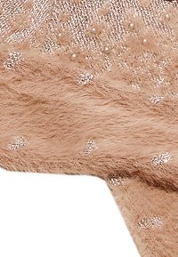 Tejido beige esponjoso con una textura suave, que presenta acentos plateados dispersos y pequeños detalles similares a perlas. Patrón sutil en el diseño.