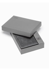 Boîte cadeau grise partiellement ouverte, révélant un portefeuille gris foncé avec une surface texturée et un logo "ombre" en relief, maintenu par des coutures contrastantes.
