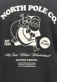 T-shirt preta de algodão com gráfico branco do Pai Natal a carregar presentes, com texto: "NORTH POLE CO." e "Step Into Winter Wonderland!"