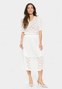 Set due pezzi bianco in pizzo composto da un top a maniche corte con scollatura a V e una gonna di lunghezza media, entrambi decorati con un motivo a scallop.