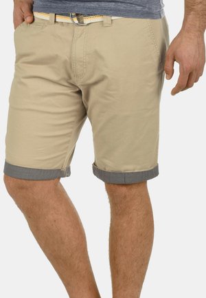 Beige bomullsshorts med oppbrett i mørkegrått. Har frontlommer og belte med oransje detaljer. Rett snitt.