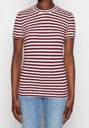 Person trägt ein eng anliegendes kurzärmeliges T-Shirt mit horizontalen weißen und dunkelroten Streifen, kombiniert mit hellblauen Jeans.