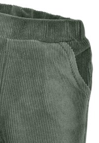 Grüne Cord-Hosen mit gerippter Textur, ausgestattet mit einem elastischen Bund und seitlichen Taschen. Nahaufnahme zeigt die Details des Stoffes.