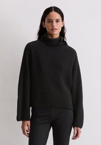Czarny sweter z wysokim kołnierzem, o luźnym kroju i długich rękawach, wykonany z fakturowanej dzianiny. Minimalistyczny i bezszwowy design.