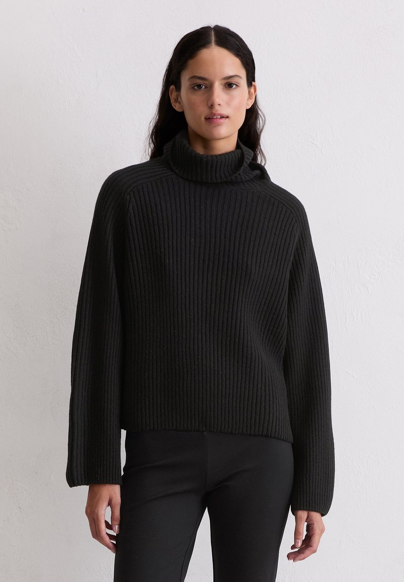 Czarny sweter z wysokim kołnierzem, o luźnym kroju i długich rękawach, wykonany z fakturowanej dzianiny. Minimalistyczny i bezszwowy design.