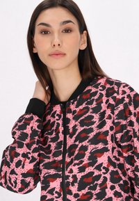 Giubbotto bomber con stampa leopardata rosa e nera, dotato di chiusura con zip, polsini e colletto a coste, realizzato in un morbido tessuto testurizzato.