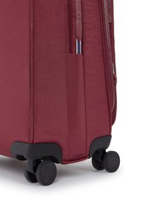 Bordeaux mjukskalväska med en texturerad yta, utdragbart handtag och svarta hjul. Har en sidoficka och kontrasterande dragkedjedetalj.