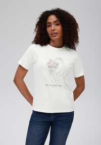 Hvit bomull T-skjorte med en linjetegning av en figur med blomster. Teksten under lyder "Ta vare på håret ditt". Korte ermer, avslappet passform.
