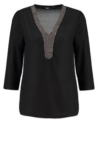 Tunic nera con scollatura a V, maniche a tre quarti e dettagli decorativi in argento lungo il collo. Tessuto morbido, vestibilità comoda.