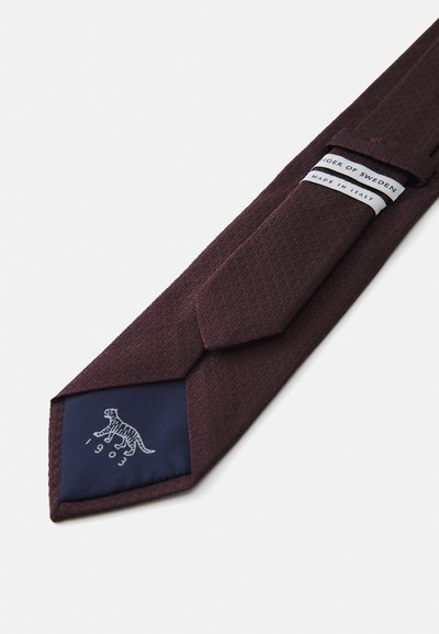 Bordeauxfarbige strukturierte Krawatte mit einer marineblauen Unterseite, die ein weißes Tigerlogo und "1903" zeigt. Das Etikett besagt "Tiger of Sweden, Made in Italy."