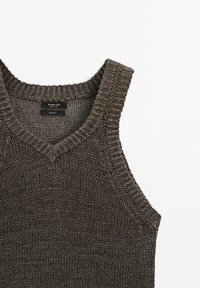 Gilet sans manches en tricot brun foncé avec col en V, bords côtelés texturés, et étiquette de la marque Massimo Dutti à l'intérieur du col.