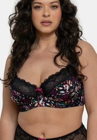 Soutien-gorge en dentelle noire avec imprimé floral présentant des couleurs vives, des bords festonnés et un petit nœud rose au centre.