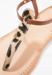 Hnědé kožené žabky s popruhem s leopardím vzorem. Měkký, texturovaný svršek a hladká béžová stélka, s prošívanými detaily.