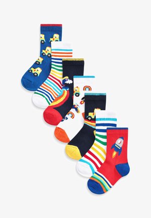 Ensemble de sept paires de chaussettes pour enfants présentant divers designs colorés : bleu avec des camions jaunes, motifs rayés, arcs-en-ciel et un motif de fusée.