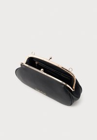 Melna ādas rokassoma ar zelta metāla rāmi, kam ir skavas aizdare un iekšējā rāvējslēdzēja kabata. Uz priekšpuses ir iegriezts uzraksts "Valentino".